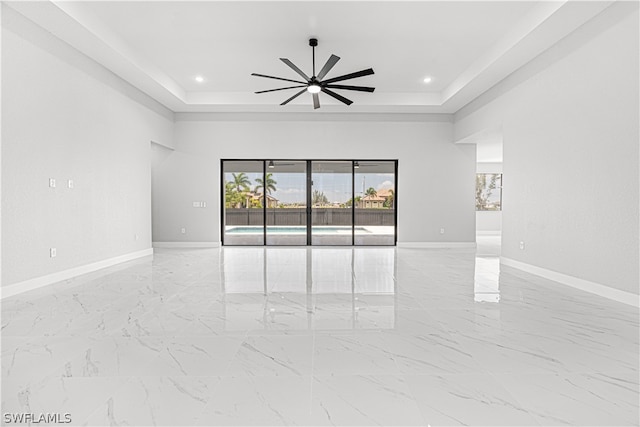 spare room featuring a raised ceiling and ceiling fan