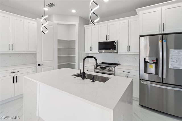 kitchen featuring sink, white cabinets, backsplash, a kitchen island with sink, and stainless steel appliances