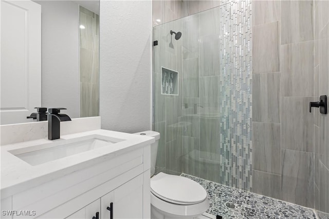 bathroom with tiled shower, vanity, and toilet