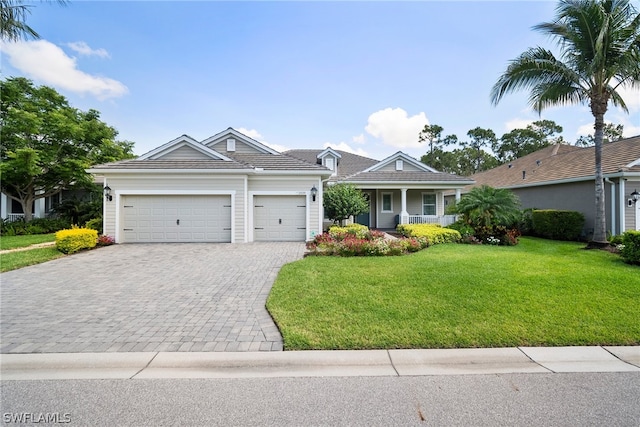 single story home featuring decorative driveway, a porch, an attached garage, a front yard, and a tiled roof