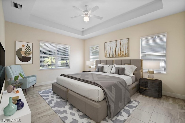 bedroom with baseboards, visible vents, and a raised ceiling