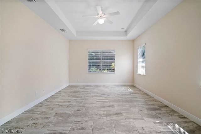 spare room featuring ceiling fan, baseboards, visible vents, and a raised ceiling