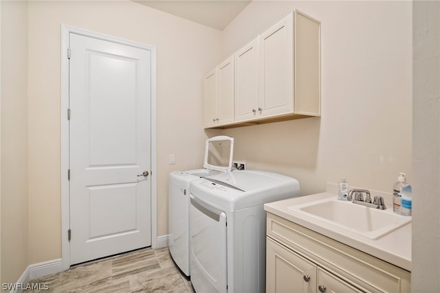 laundry room featuring separate washer and dryer, a sink, cabinet space, and baseboards