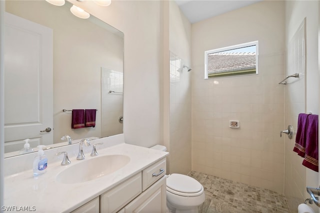 bathroom with vanity, a tile shower, and toilet