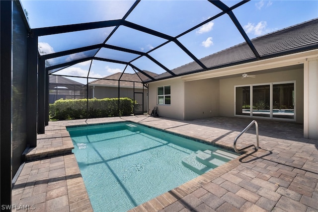 outdoor pool with glass enclosure, a patio area, and ceiling fan