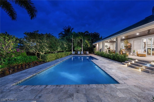 pool at night featuring a patio area