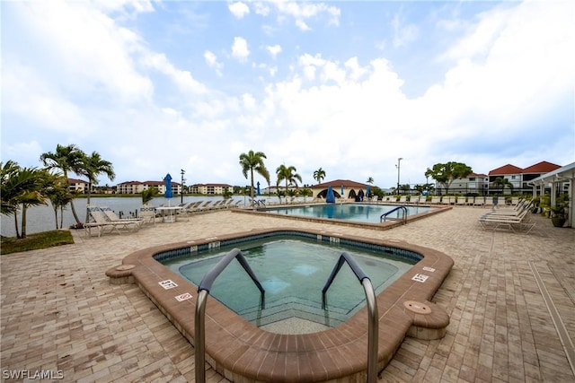 pool with a patio area and a community hot tub