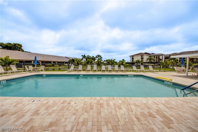 pool with a patio area and fence