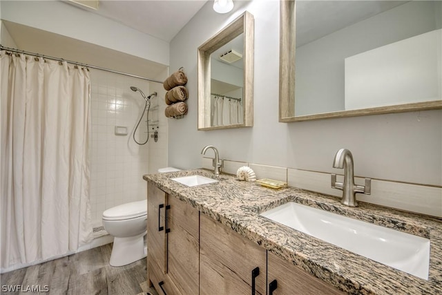 full bathroom featuring double vanity, toilet, a sink, and wood finished floors