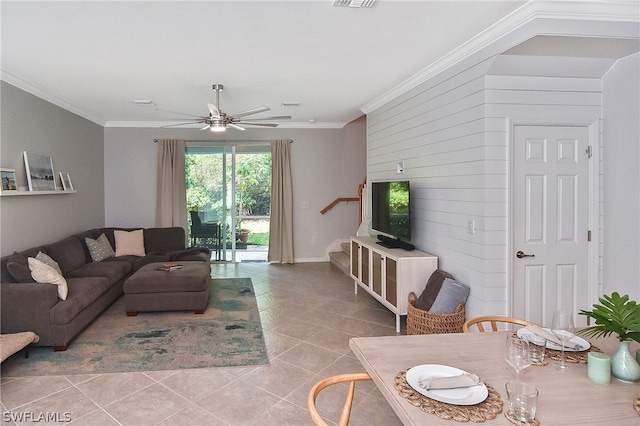 tiled living room with ceiling fan, wood walls, crown molding, and stairs