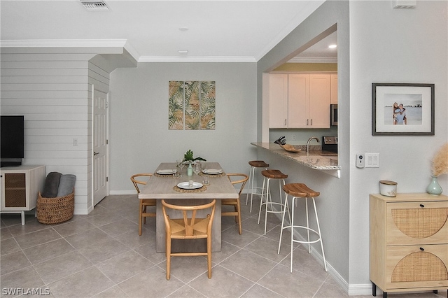 tiled dining room featuring crown molding