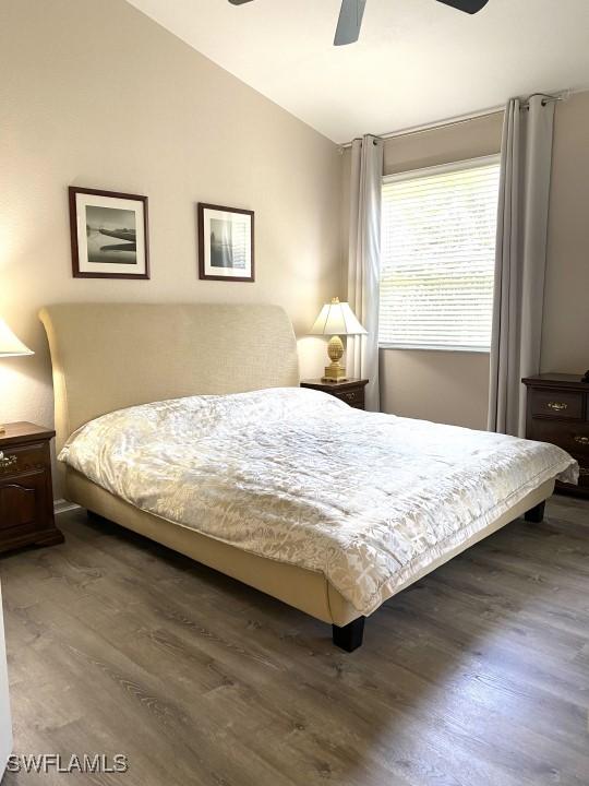 bedroom featuring ceiling fan, dark wood-type flooring, and lofted ceiling