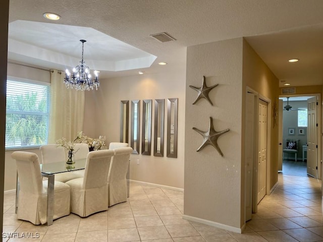 dining area featuring a chandelier, light tile patterned floors, and a raised ceiling