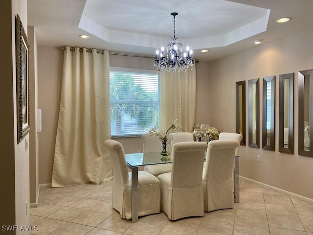 dining space featuring a tray ceiling, light tile patterned floors, and an inviting chandelier