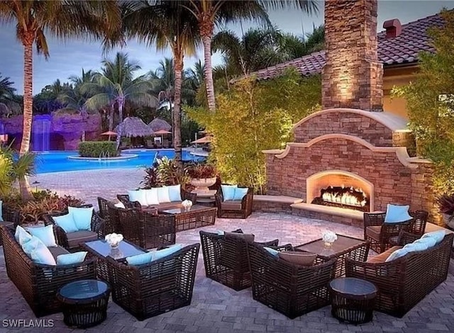 patio terrace at dusk featuring an outdoor living space with a fireplace