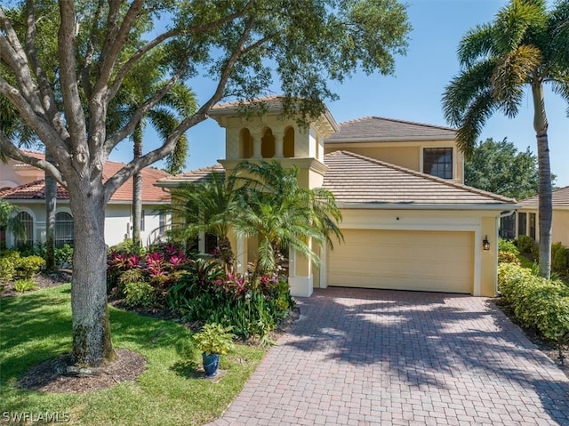 mediterranean / spanish-style home with a garage and a front lawn