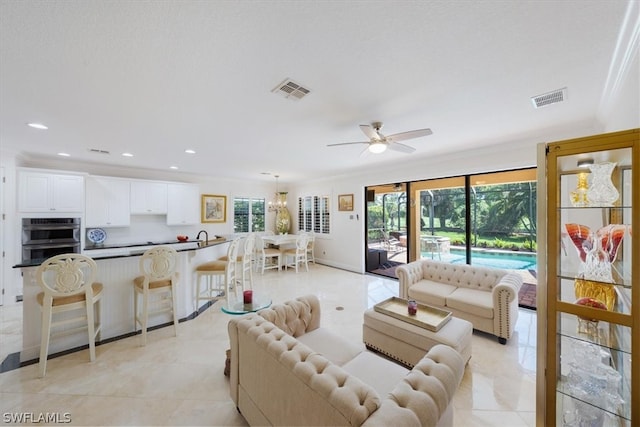 tiled living room featuring ceiling fan and crown molding