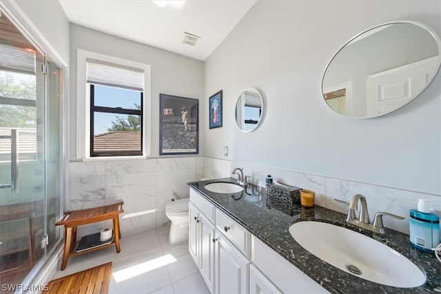 bathroom featuring dual bowl vanity, tile flooring, toilet, and a shower with door