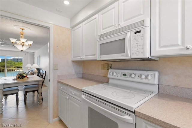 kitchen featuring white appliances, white cabinets, decorative light fixtures, a notable chandelier, and light tile flooring