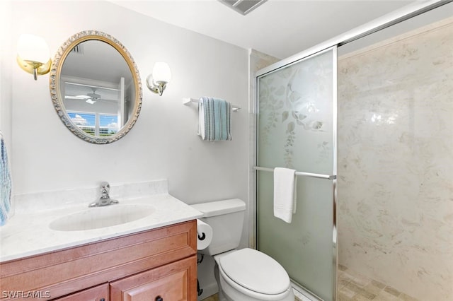 bathroom featuring a shower with shower door, ceiling fan, vanity, and toilet