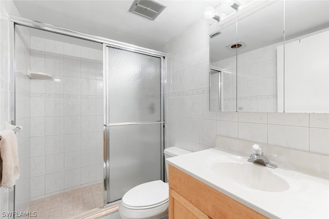 bathroom with tile walls, a shower with door, oversized vanity, and toilet