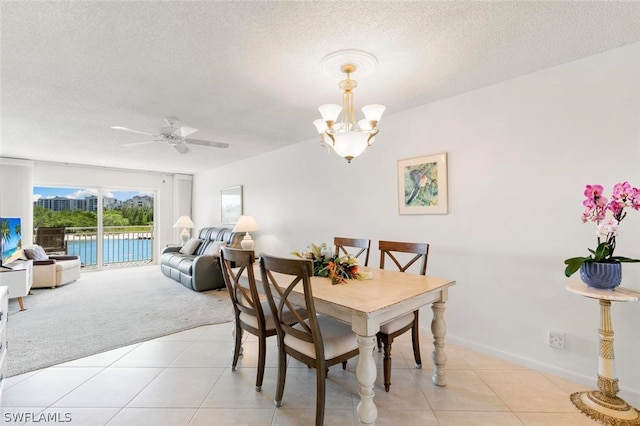 tiled dining space with ceiling fan with notable chandelier and a textured ceiling