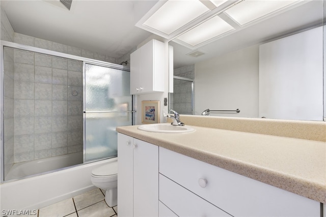 full bathroom featuring tile flooring, vanity, toilet, and bath / shower combo with glass door