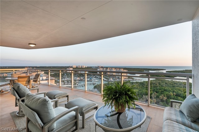 balcony at dusk featuring a water view