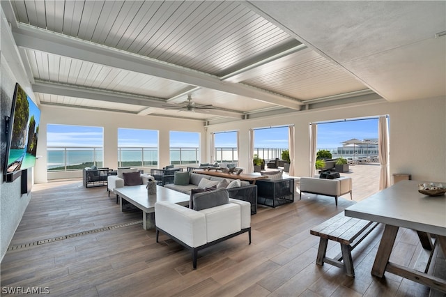 living room with beam ceiling, hardwood / wood-style floors, and a wealth of natural light