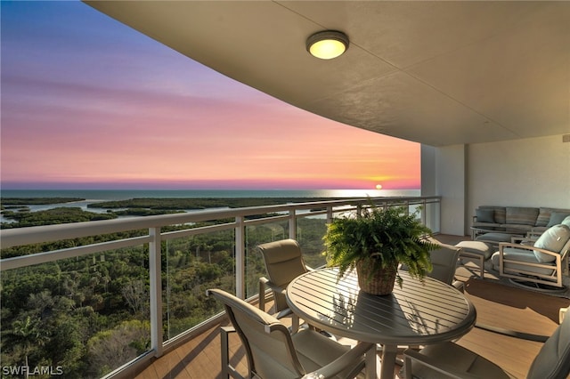 balcony at dusk featuring a water view