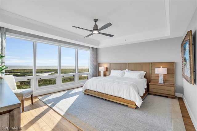 bedroom featuring a tray ceiling, light wood-type flooring, and ceiling fan