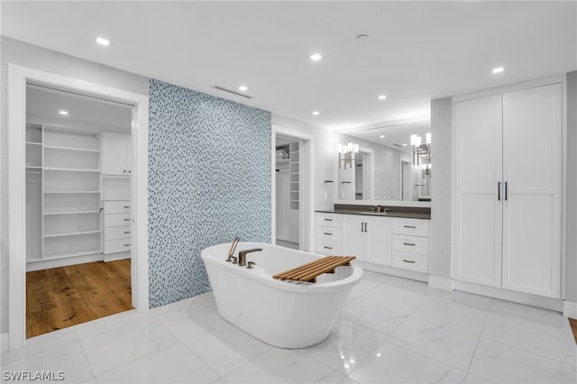 bathroom with a washtub, wood-type flooring, and vanity