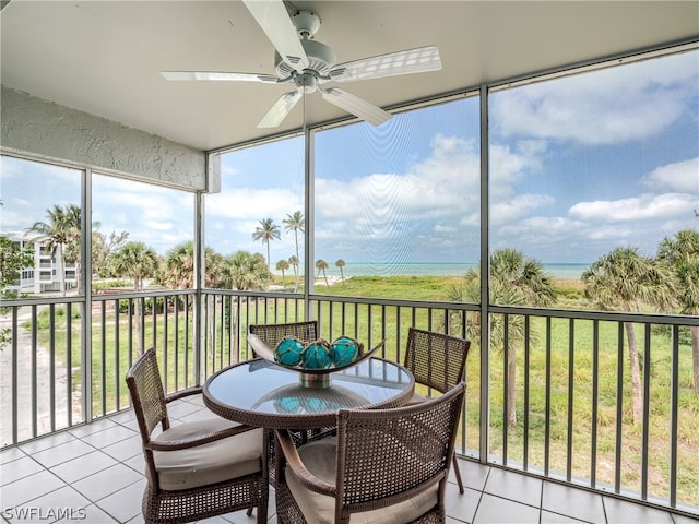 sunroom with ceiling fan and a water view