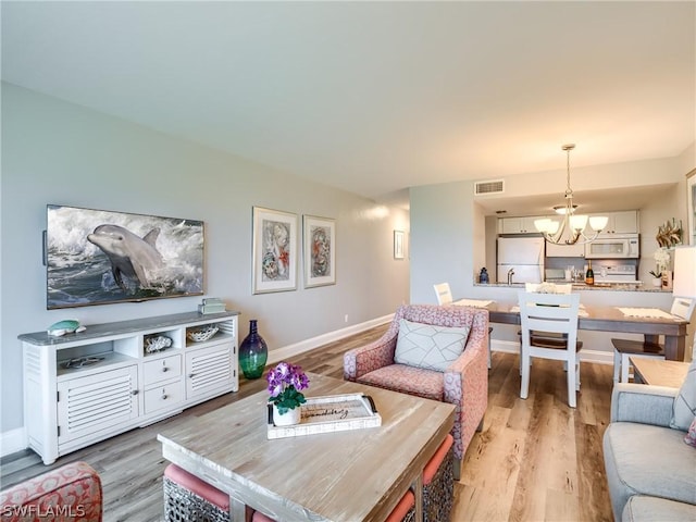 living room featuring light hardwood / wood-style flooring and an inviting chandelier