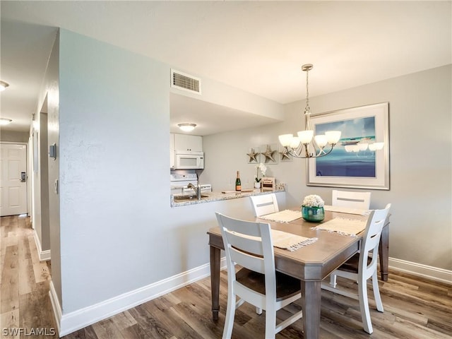 dining room with wood-type flooring and an inviting chandelier