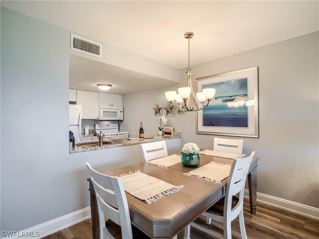 dining room featuring dark wood-type flooring, sink, and a notable chandelier