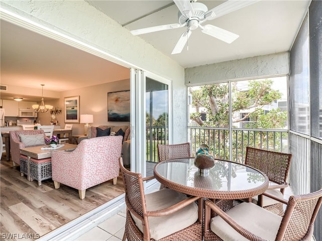 sunroom with ceiling fan with notable chandelier