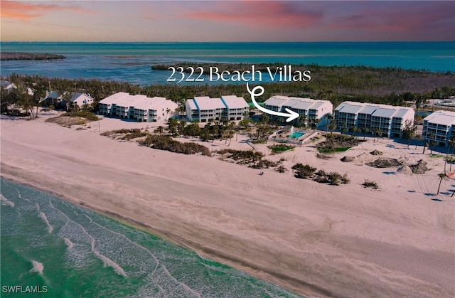 aerial view at dusk with a water view and a view of the beach