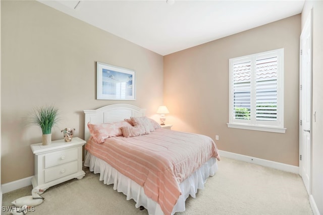bedroom with baseboards and light colored carpet