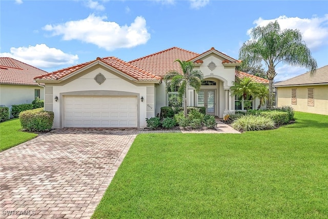 mediterranean / spanish-style home with stucco siding, a tile roof, a front lawn, and decorative driveway