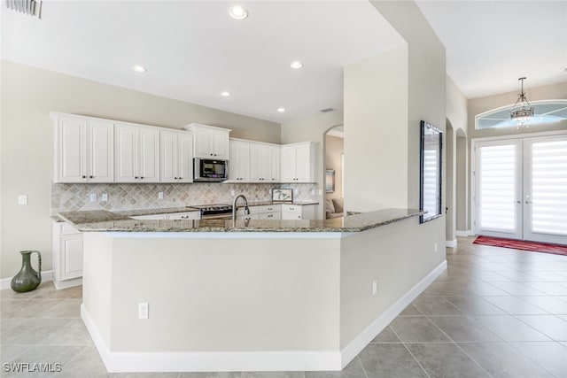 kitchen with white cabinets, kitchen peninsula, stone countertops, and french doors