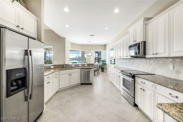 kitchen with white cabinets, hanging light fixtures, sink, appliances with stainless steel finishes, and dark stone countertops