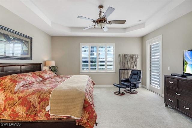 carpeted bedroom featuring a tray ceiling, baseboards, access to exterior, and a ceiling fan