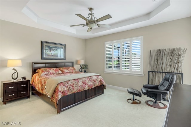 bedroom featuring light carpet, a raised ceiling, and ceiling fan