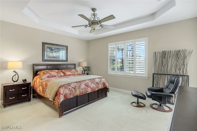bedroom featuring baseboards, ceiling fan, light carpet, and a raised ceiling