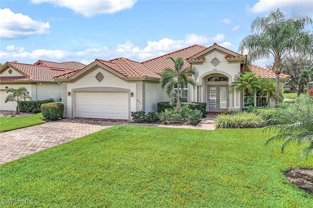 mediterranean / spanish home featuring a tiled roof, decorative driveway, a front lawn, stucco siding, and french doors