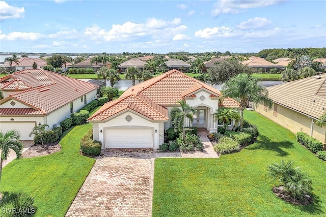 view of front of house featuring a tiled roof, decorative driveway, a garage, and a residential view
