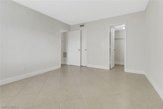 unfurnished bedroom featuring ensuite bathroom and light tile floors