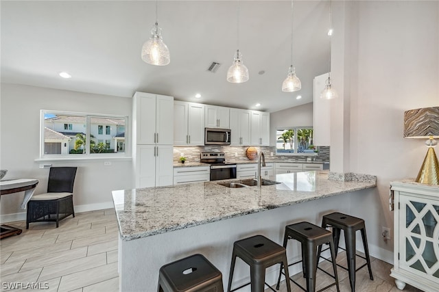 kitchen with stainless steel appliances, kitchen peninsula, tasteful backsplash, and pendant lighting