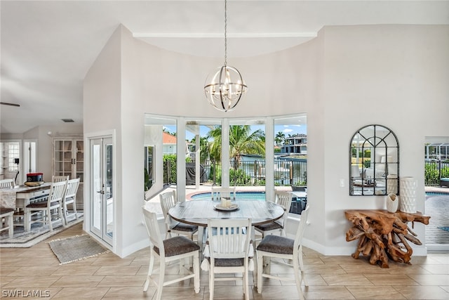 dining space with an inviting chandelier, a towering ceiling, and french doors